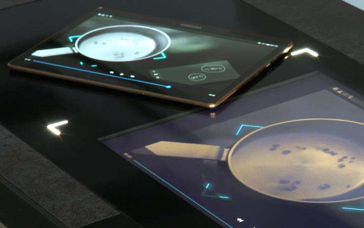 A vitroceramic cooking surface with integrated display and tablet next to it