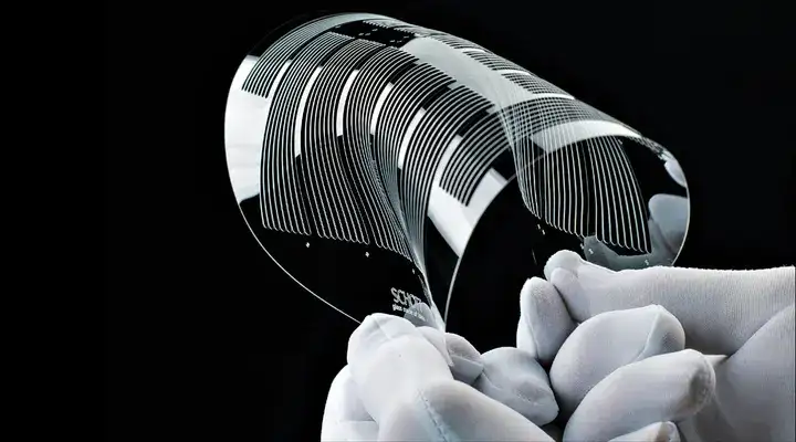 Gloved hands bending a structured glass wafer made from SCHOTT FLEXINITY® 