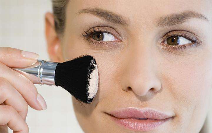 Female applying face powder using a make-up brush