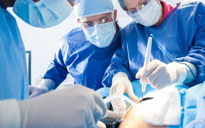 Equipe de cirurgiões em um centro cirúrgico realizando uma terapia médica com luz