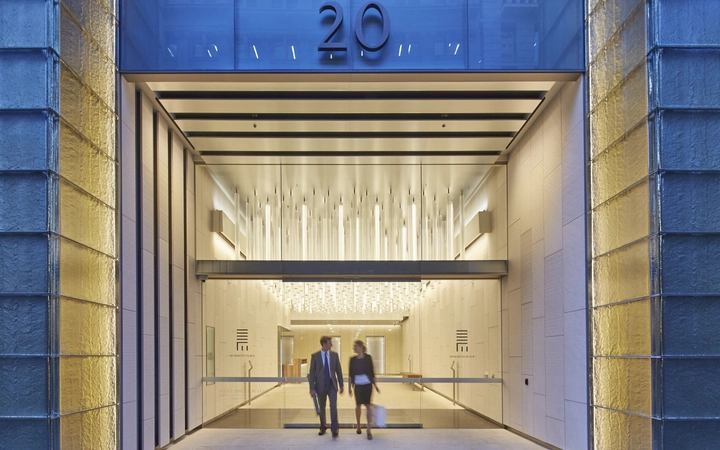 Homme et femme quittant un immeuble de bureaux avec une installation en verre SCHOTT emplie de lumière