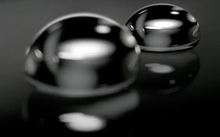 Close-up of two water drops on a dark vitroceramic cooktop