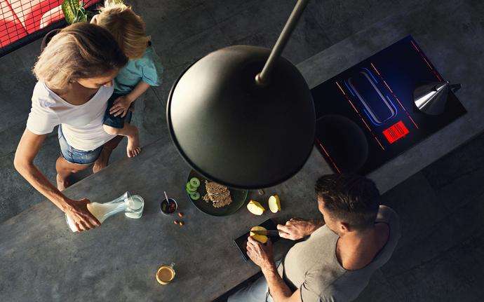 Bird’s eye-view into a kitchen with a family and their SCHOTT CERAN® cooktop featuring the EXCITE® light