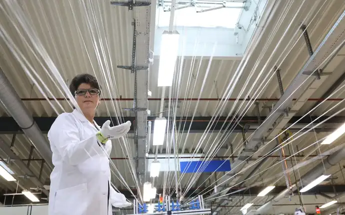 Um funcionário da SCHOTT com várias fibras ópticas de vidro durante o processo de produção