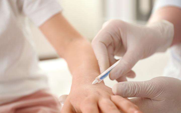 Close up of a doctor's gloved hands giving an injection to a patient