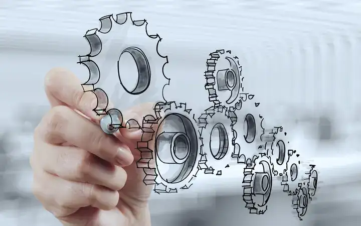 Hand holding an illustration of a series of cogs