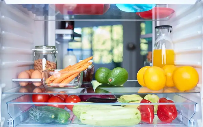 Interior of a domestic fridge with glass shelves stocked with food