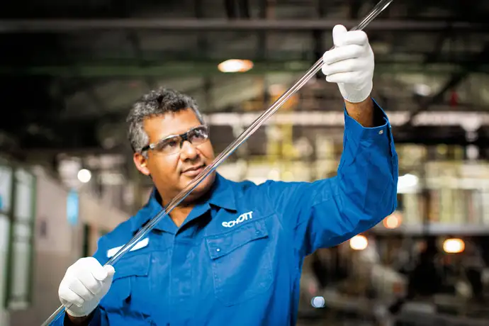 Engenheiro do sexo masculino inspeciona um bastão de vidro