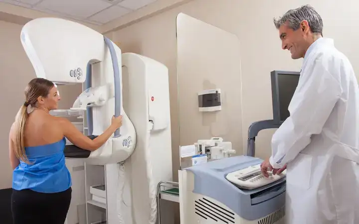 Arzt im Gespräch mit einer Patientin, die mit medizinischer Ausrüstung in einem Krankenhaus untersucht wird