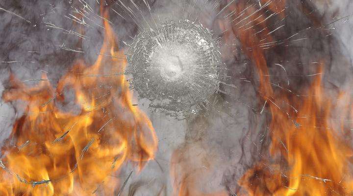 Safety glass after impact with fire in background
