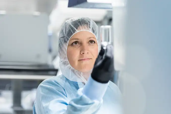 Cientista do sexo feminino em uma sala limpa ajustando um equipamento
