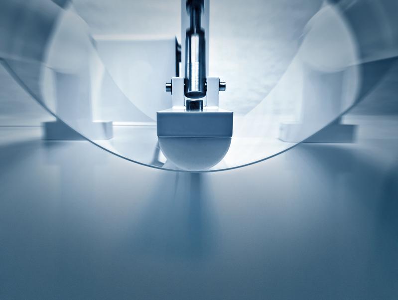 Máquina de laboratório realizando um teste de dobra em uma amostra de vidro ultrafino