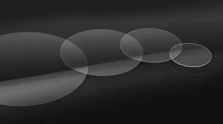 Four clear circular samples of SCHOTT MEMpax® thin borosilicate glass on a black background