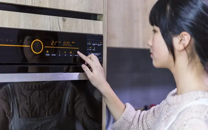 Young female operating a touchscreen panel on a modern oven