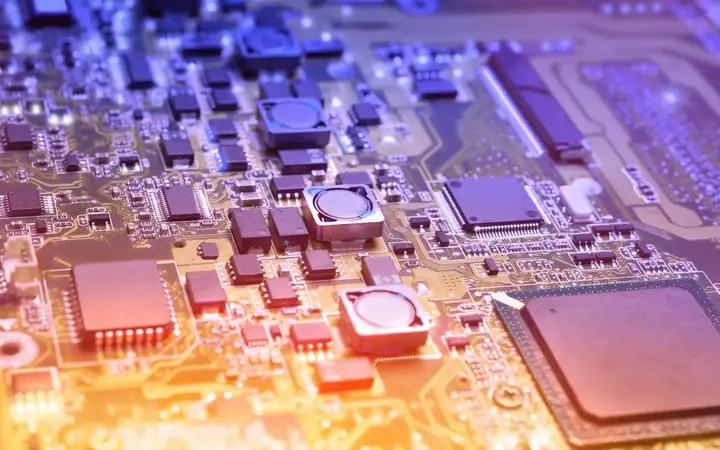 Electronics circuit board under orange and purple light