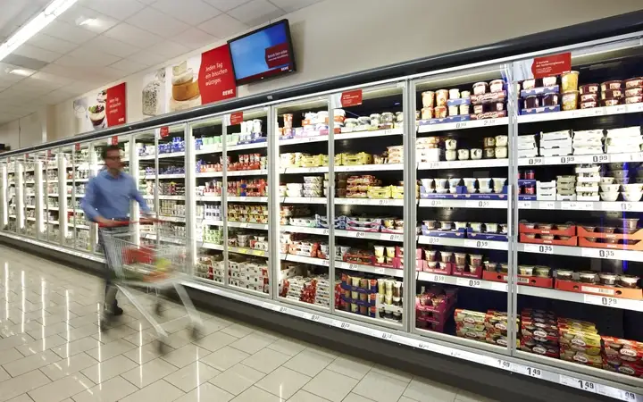 Man pushing a trolley in a supermarket freezer aisle