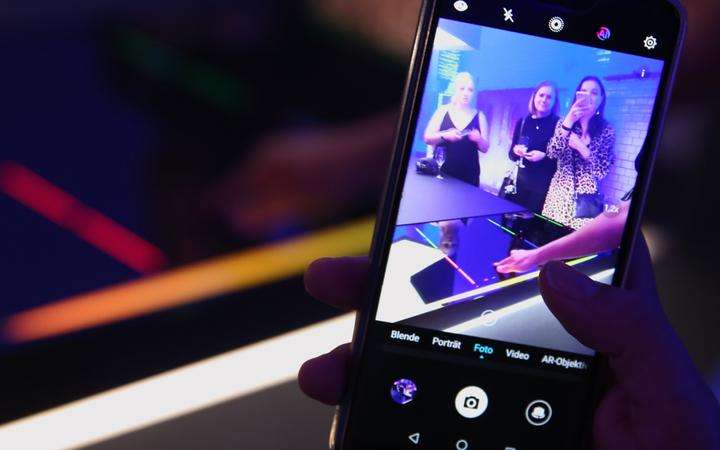 Looking through a smartphone display, seeing people testing the new CERAN EXCITE® glass-ceramic cooktop