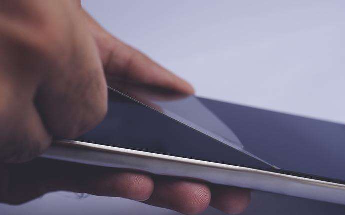 Hand removing a protective glass cover from a smartphone
