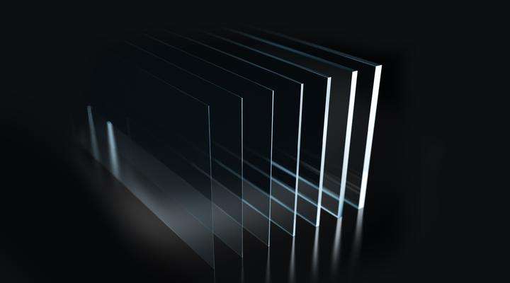 Series of clear glass sheets of different thicknesses on a dark background