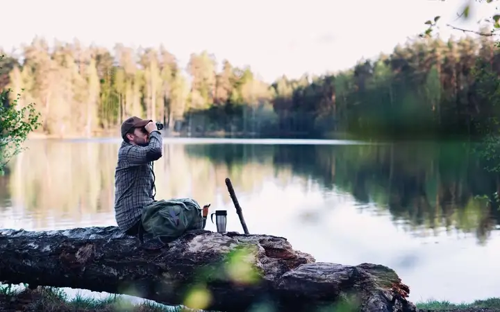 Man looking through a pair of high-powered binoculars on a lake