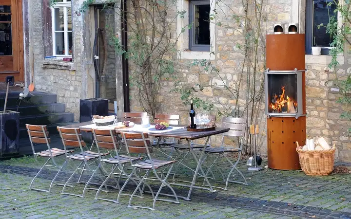 Gartenmöbel neben holzbeheiztem Außenkamin mit SCHOTT ROBAX® Feuerschutz