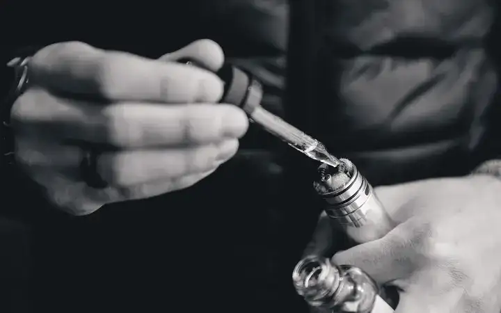 Close up of a man filling an e-cigarette or vaporizer