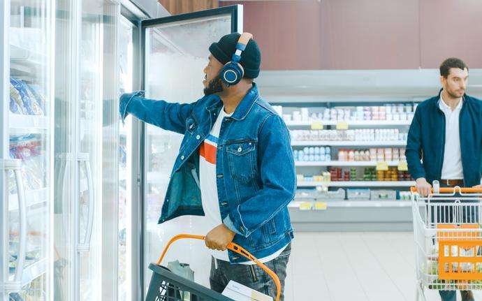 A man chooses a frozen product from a freezer in a supermarket