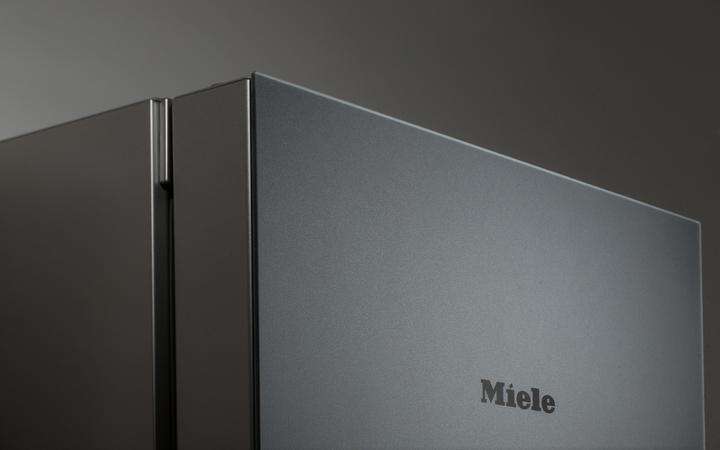 Close up of a Miele refrigerator with matt black glass front