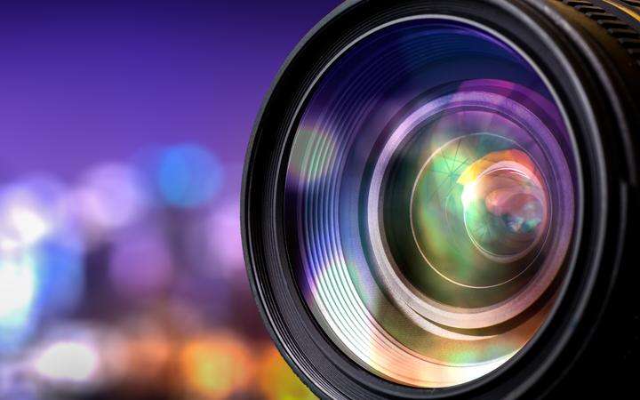Close up of a camera lens with blurred city landscape background